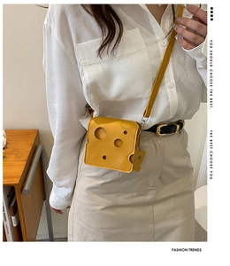 Close-up of a yellow cheese-shaped mini crossbody bag with hollow holes and a shoulder strap