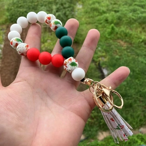 Detail of Christmas silicone bead keychain featuring Santa patterns and green tassels