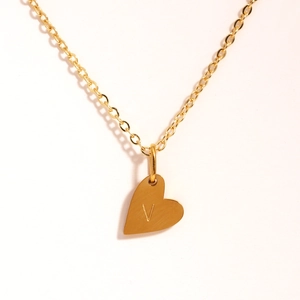 Détail du collier cœur en or avec la lettre V gravée sur le pendentif élégant pour femme