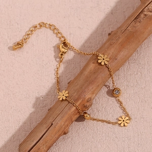 Detailed view of 18K gold plated flower bracelet with rhinestones on a wooden branch