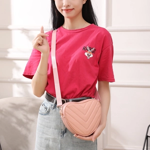 Pink heart-shaped crossbody bag with V-quilted pattern and adjustable strap on model