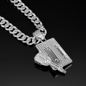 Macro shot of silver hip-hop cassette pendant with Cuban link chain on black background