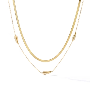 Detail of a gold double-layer necklace with snake chain and three leaf-shaped pendants