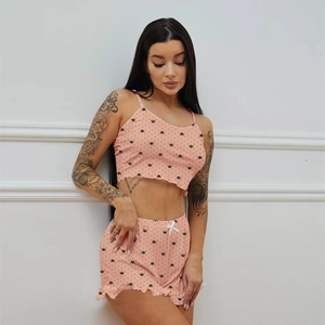 Close-up of peach pajama set with black crown prints and white bow on ruffled shorts