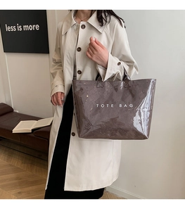 Minimalist glossy brown leather tote bag with white TOTE BAG text shown on a model