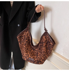 Close-up of a large leopard print tote bag with brown leather brand tag and slim shoulder straps