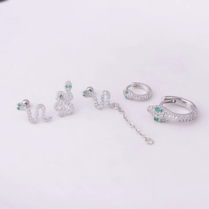 Silver snake earring set with green eyes and sparkling crystals on white background