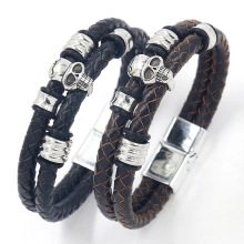 Detail of woven leather bracelets with skull charms and metallic beads in black and brown