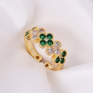 Anello aperto a quadrifoglio dorato con pietre verdi e bianche su seta bianca fine