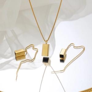 Detail of gold geometric jewelry set with rectangle necklace and long tassel earrings