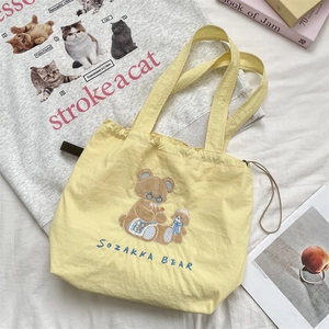 Close-up of cute bear embroidery and drawstring closure on yellow canvas tote bag