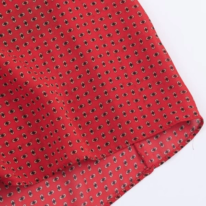 Vue détaillée du tissu rouge avec motif géométrique noir et couture d'ourlet de qualité