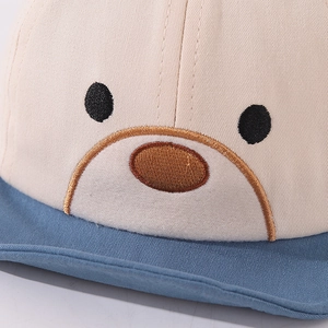 Close-up of cute cartoon bear embroidery on soft cotton baby baseball cap with blue brim