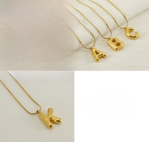 Close-up of polished 18K gold plated stainless steel bubble letter pendants and snake chain