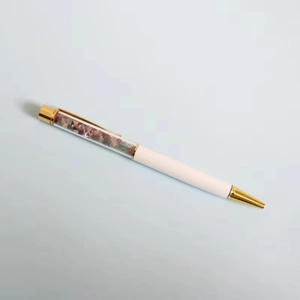 Dettaglio di elegante penna a sfera bianca con pietre di cristallo viola e verdi decorative