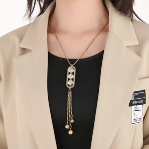 Detail of long tassel necklace with zircon stones and gold finish on a model