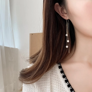 Elegant gold long drop tassel earrings with white pearls shown on a female model