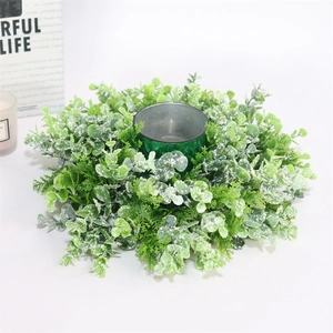 Detail of eucalyptus wreath candle holder with frosted leaves and green glass jar