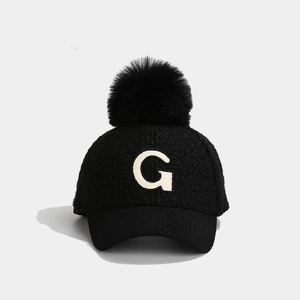 Detail der schwarzen Wintermütze für Kinder mit G-Stickerei und flauschigem Bommel