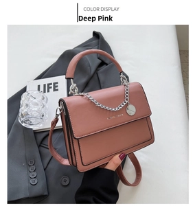 Close-up of the dark pink leather bag featuring a silver chain and circular pendant detail