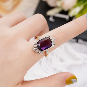 Close-up of a vintage gold ring featuring a large rectangular purple gemstone on finger