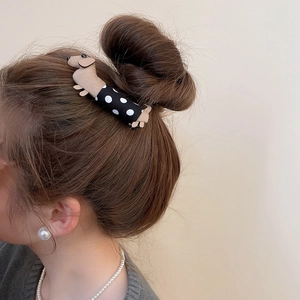 Detailed view of a polka dot dachshund fabric hair clip worn on a bun hairstyle