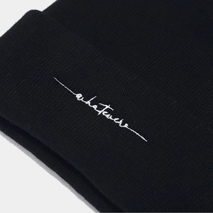 Black knitted beanie with white letter embroidery shown in close-up perspective