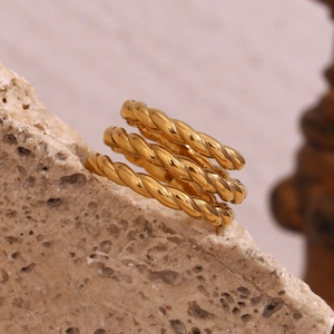 Macro view of gold 18K plated stainless steel triple layered twisted ring on a stone