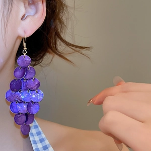 Close-up of layered purple shell tassel drop earrings on model for a beach holiday look