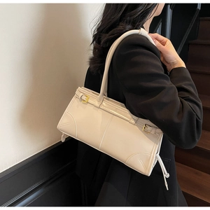 Woman in black suit styling a white PU leather underarm bag on a shoulder in a modern setting