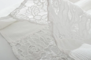 Close-up of delicate white lace pattern with intricate floral cutouts and breathable texture