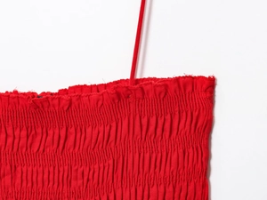 Detail of red cotton midi dress with spaghetti straps and elasticated smocked bodice texture