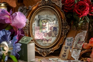 Artistic detail of vintage butterfly stickers and floral ephemera in a gold frame