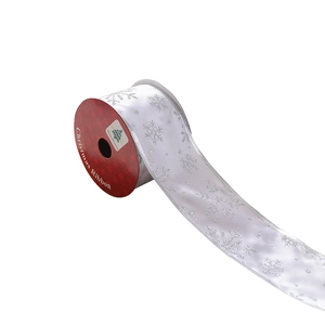 White Christmas ribbon with silver glitter snowflakes on a red spool for holiday decor