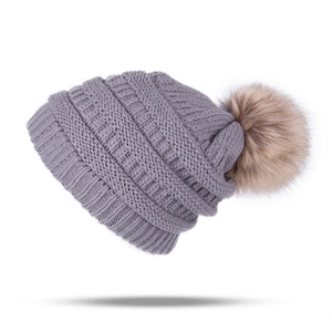 Cozy purple winter knitted beanie for kids featuring a large tan faux fur pom-pom