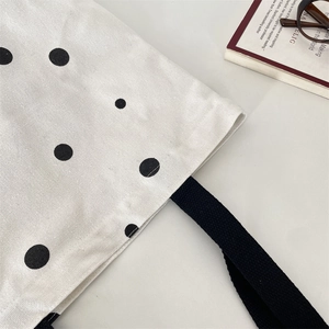 Detail shot of the large capacity canvas tote bag showing black polka dots and woven handles