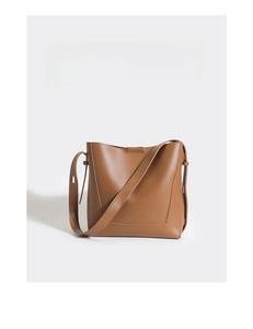 Macro detail of brown leather bucket bag showing smooth texture and clean minimalist stitching