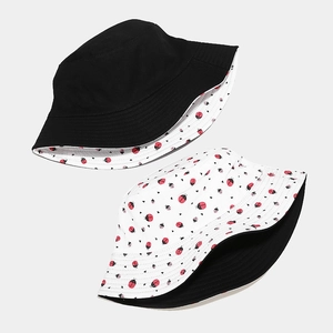 Detail of reversible fisherman hat showing solid black side and cute ladybug heart pattern