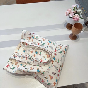 Close-up of cream canvas tote bag featuring colorful cartoon dog illustrations and fabric label