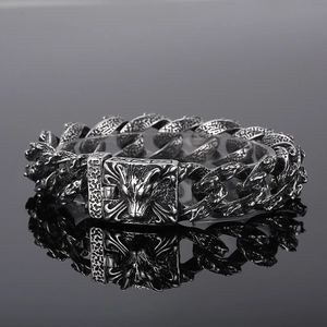 Close-up of vintage silver wolf head buckle and textured steel chain on men's bracelet