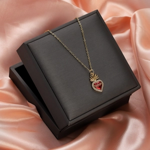 Close-up of heart pendant necklace with red center on black gift box and pink silk