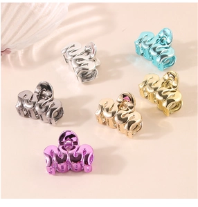 Detail of small metallic hair clips in wave design with silver and gold finish