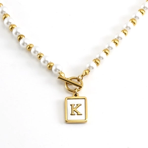 Golden OT buckle pearl necklace with stainless steel letter K pendant on white background