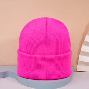 Detailed texture of rose pink ribbed knit beanie hat on a minimalist display stand