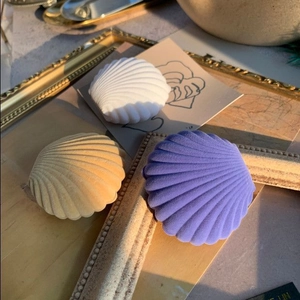 Detailed view of white, yellow and purple shell shaped flocked jewelry boxes in sunlight