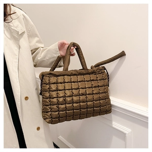 Close-up of brown quilted tote bag showing padded diamond texture and handle detail