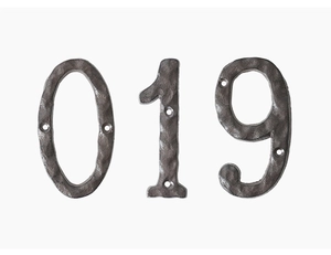 Detail of vintage cast iron house numbers 0, 1, and 9 with rustic hammered metal texture