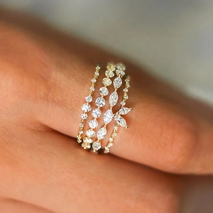 Detail of four stackable gold rings set with sparkling marquise and round cut white zircons