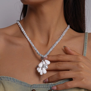 Close-up of white acrylic water drop pendant necklace with silver woven chain on model