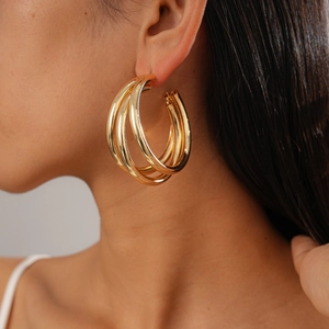 Close-up of gold geometric layered hoop earrings with a shiny metallic finish on model